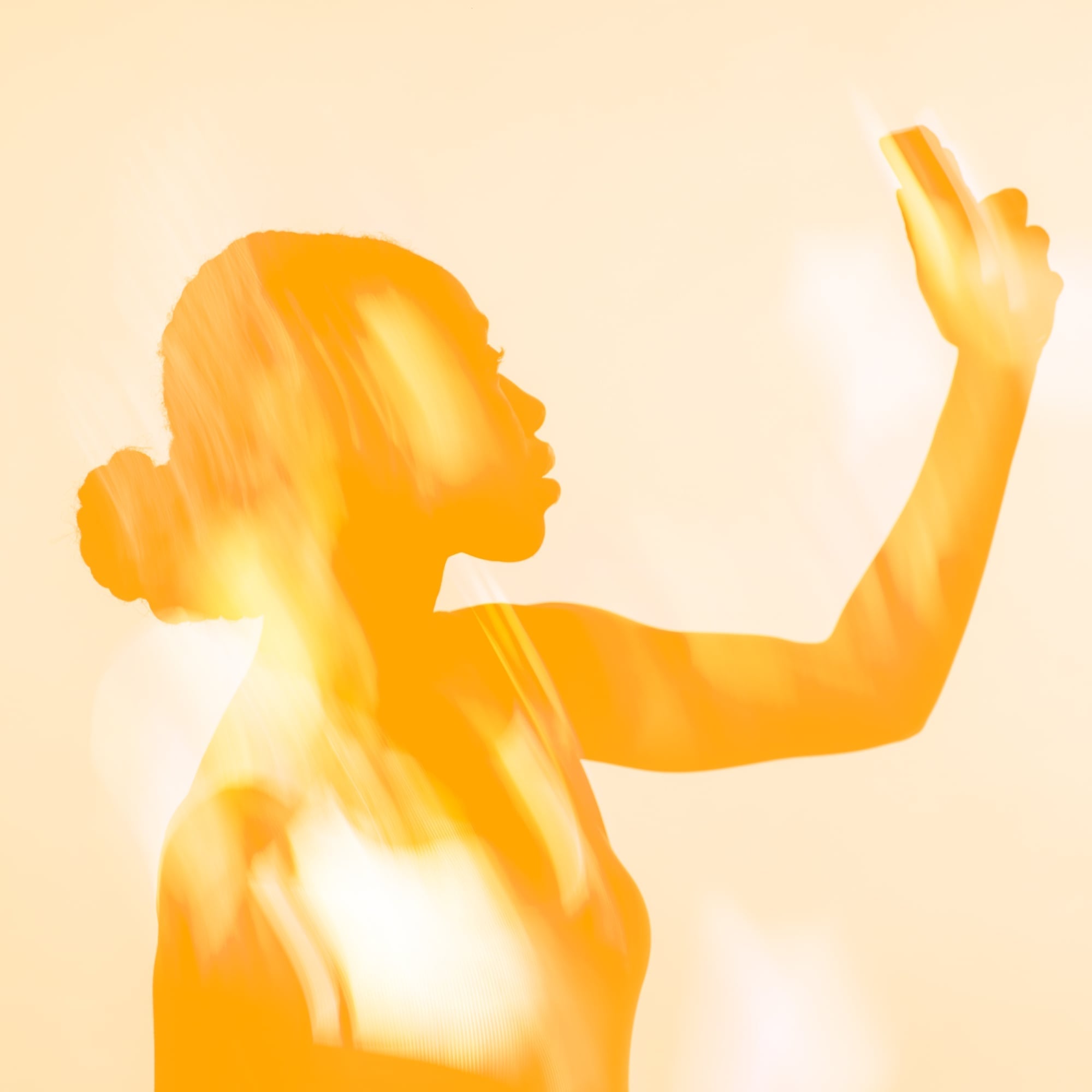 orange glowing silhouette woman holding phone amber background