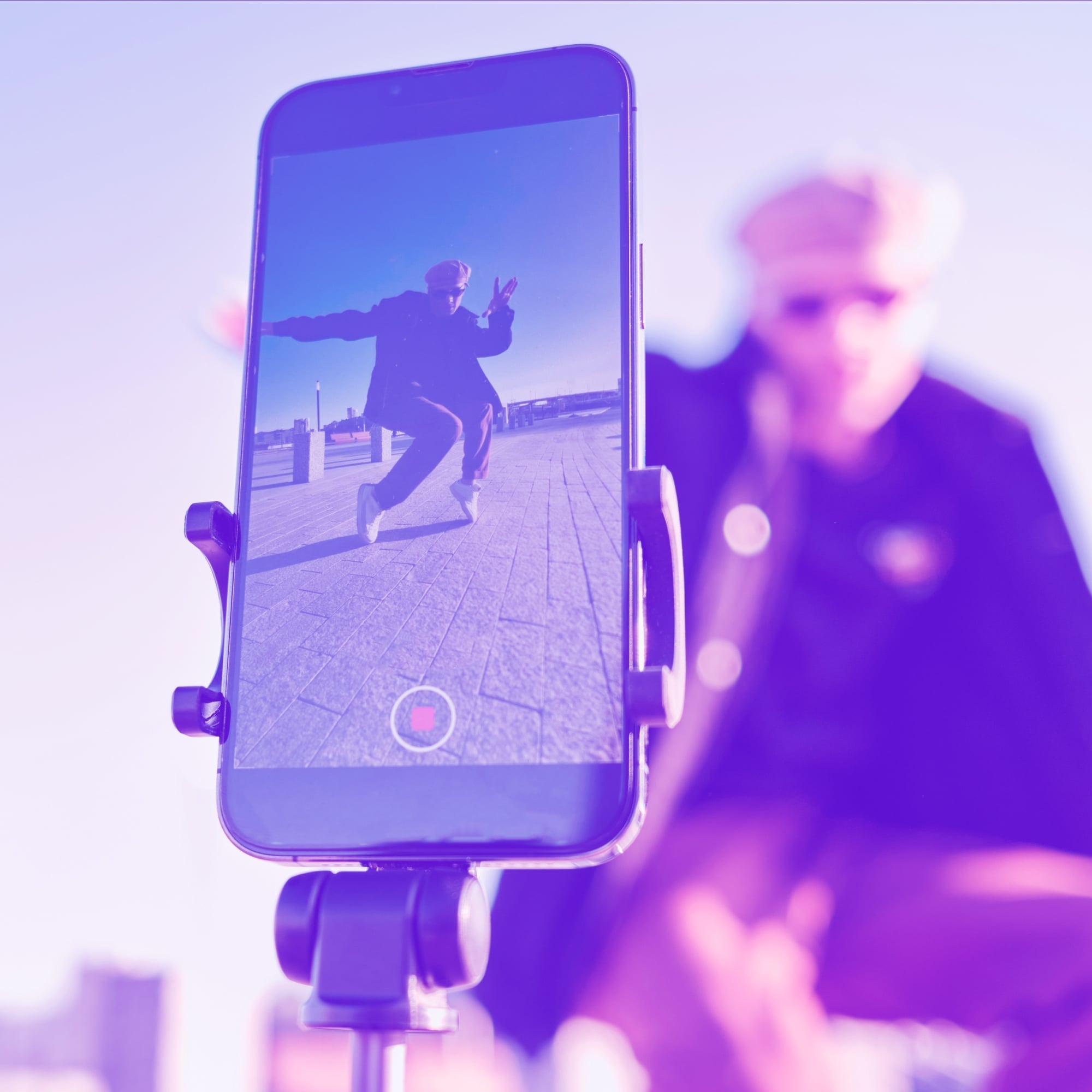 smartphone on tripod recording man jumping outdoors purple toned