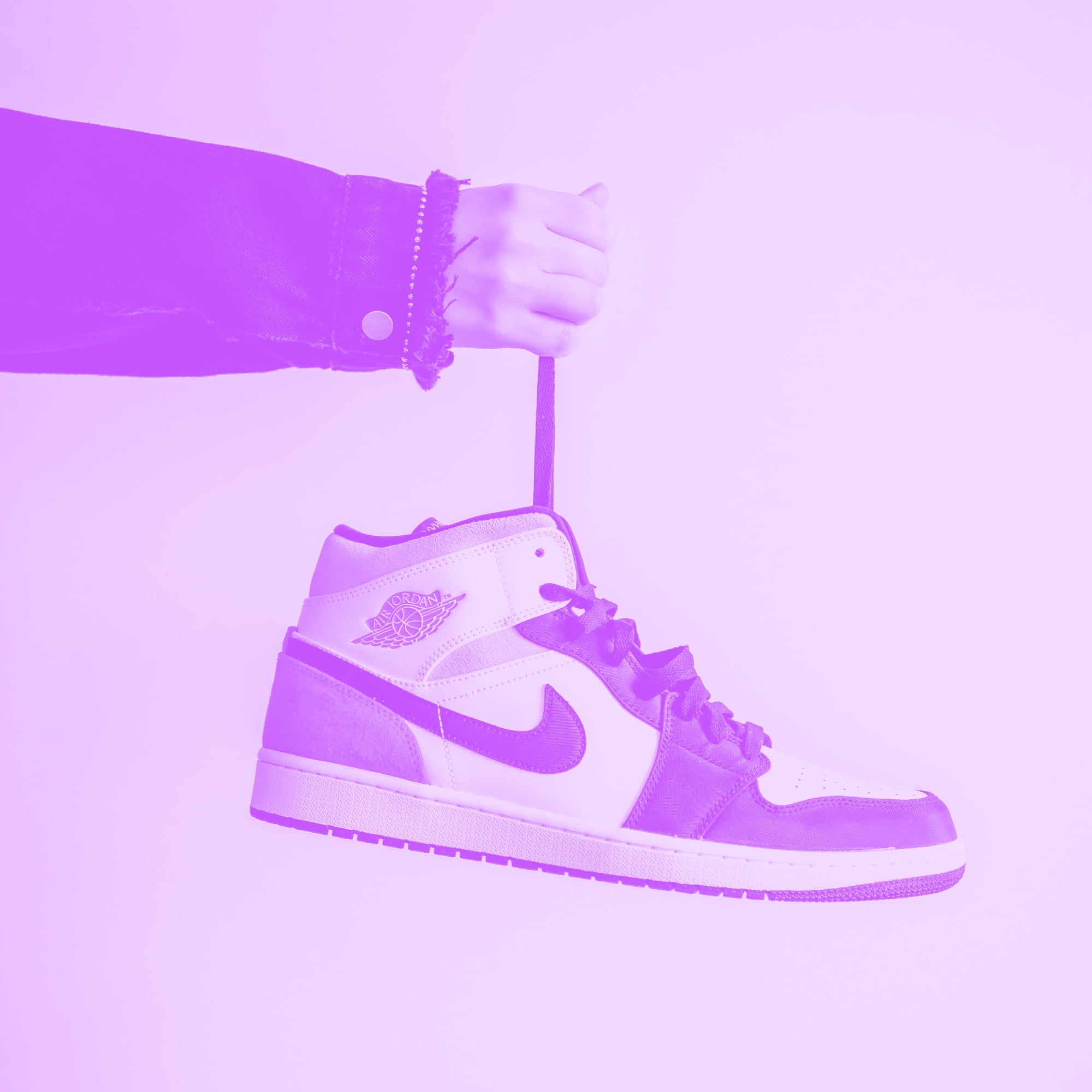hand holding air jordan 1 sneaker by lace dangling purple toned