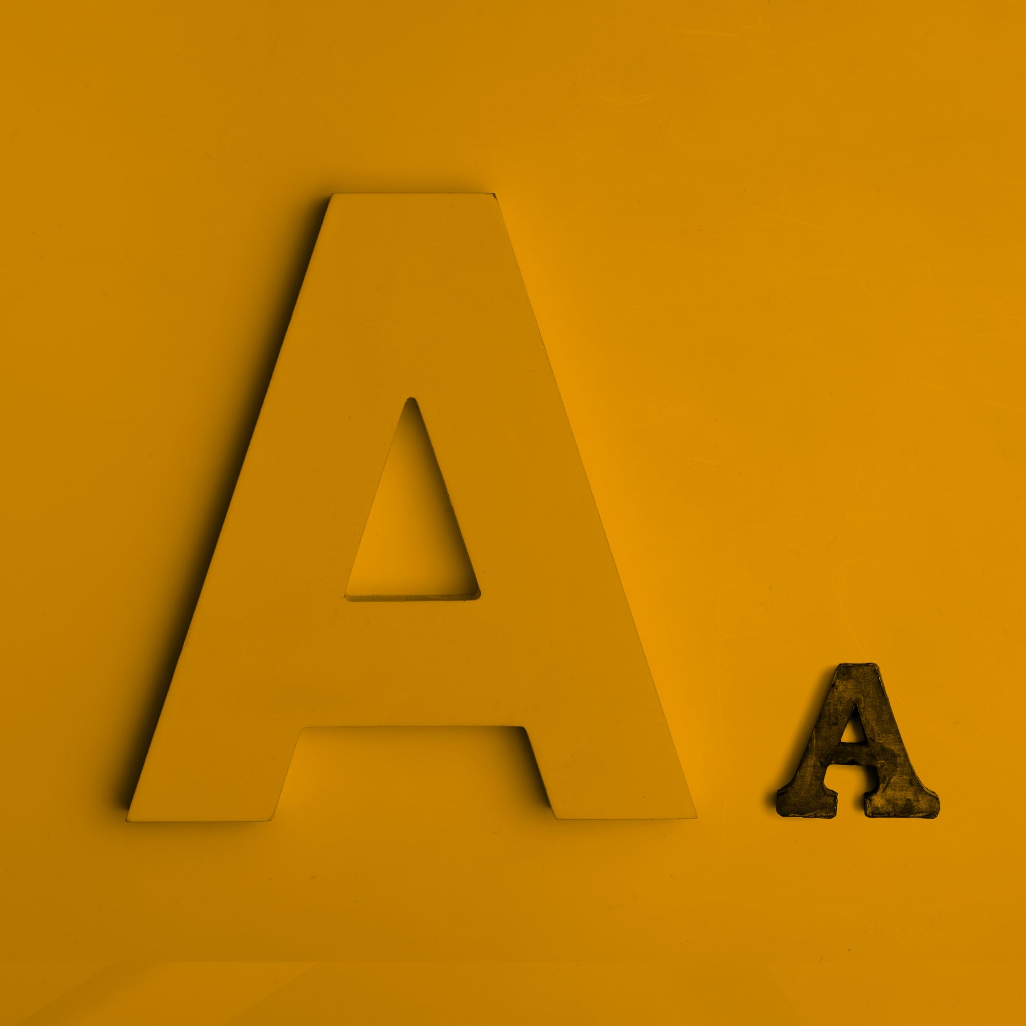 large letter a font comparison two sizes golden amber background typography