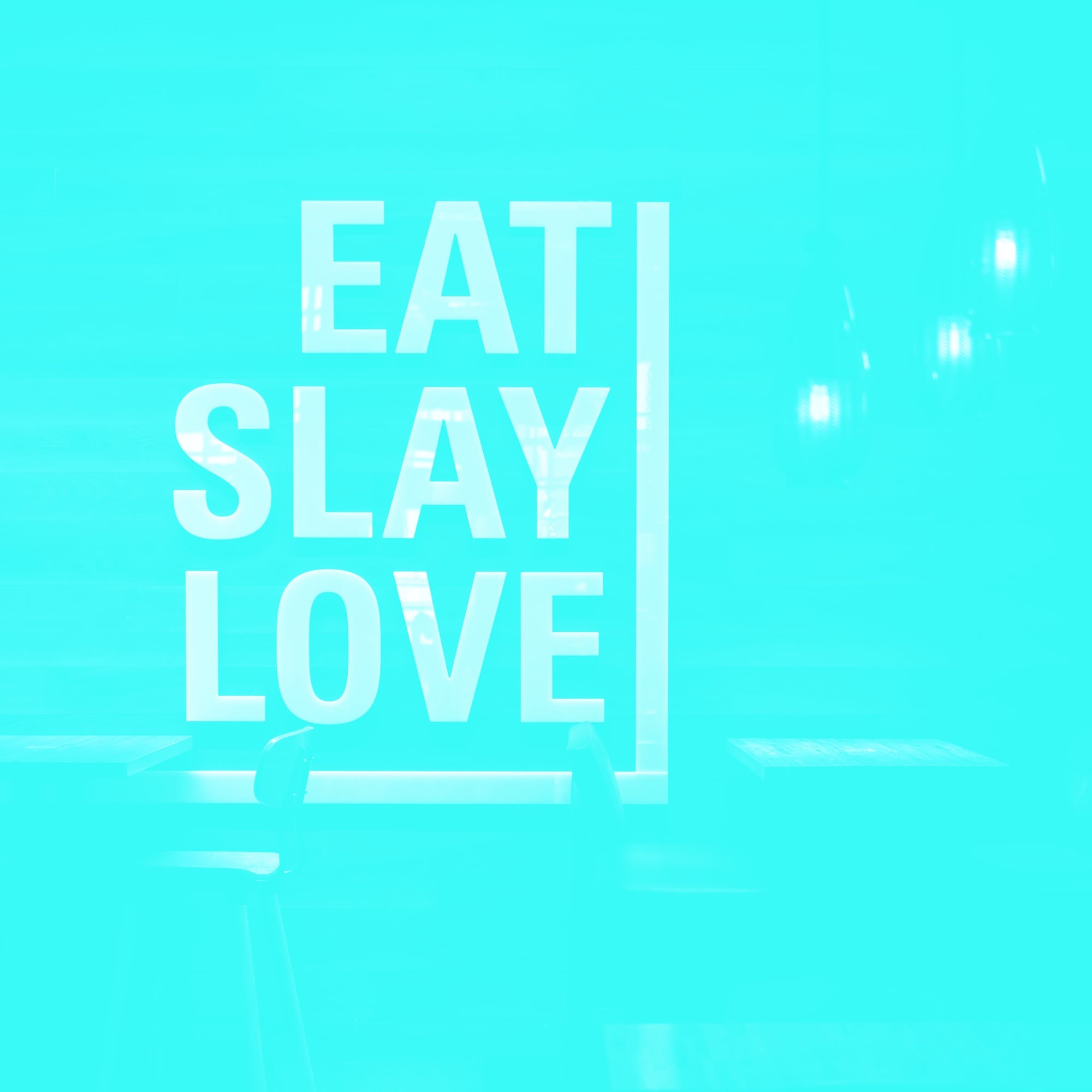 eat slay love typography sign on teal restaurant interior wall