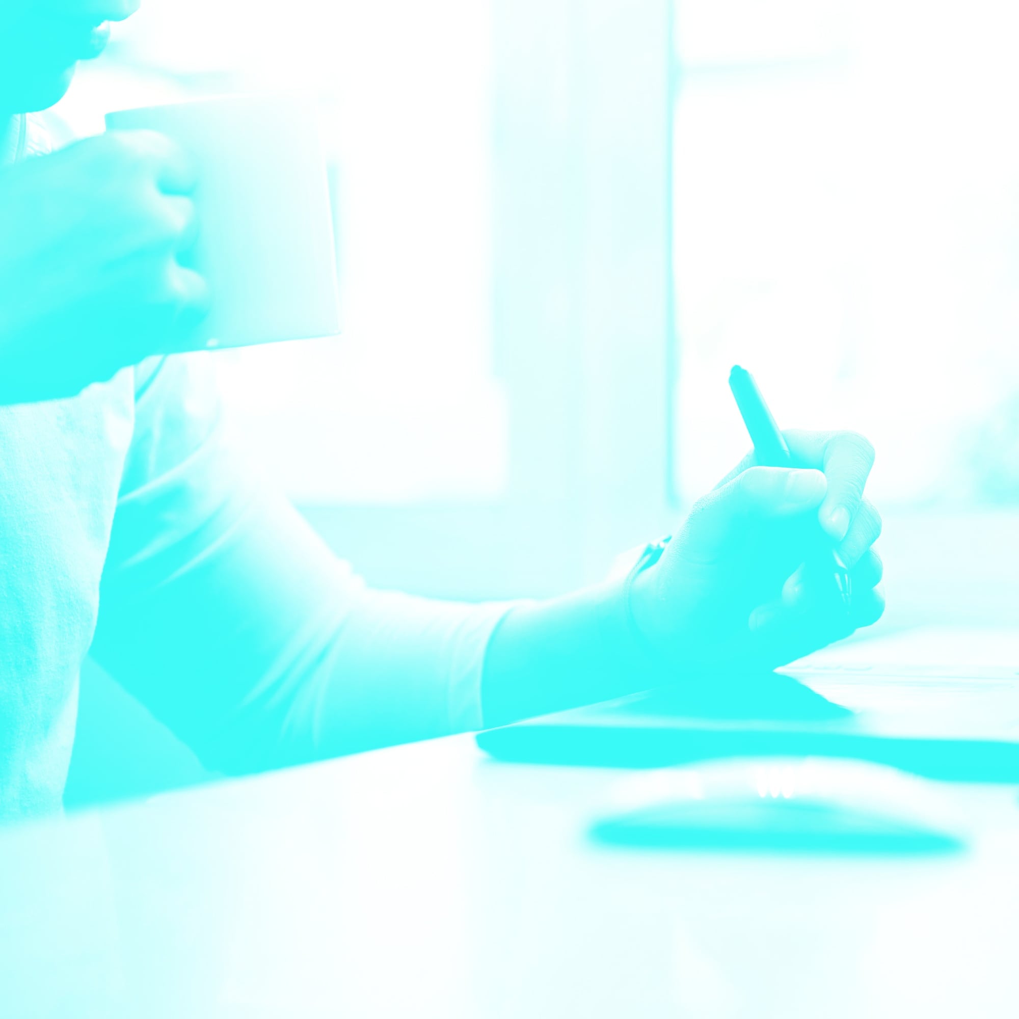 designer sketching with stylus pen at desk while holding coffee cup teal toned