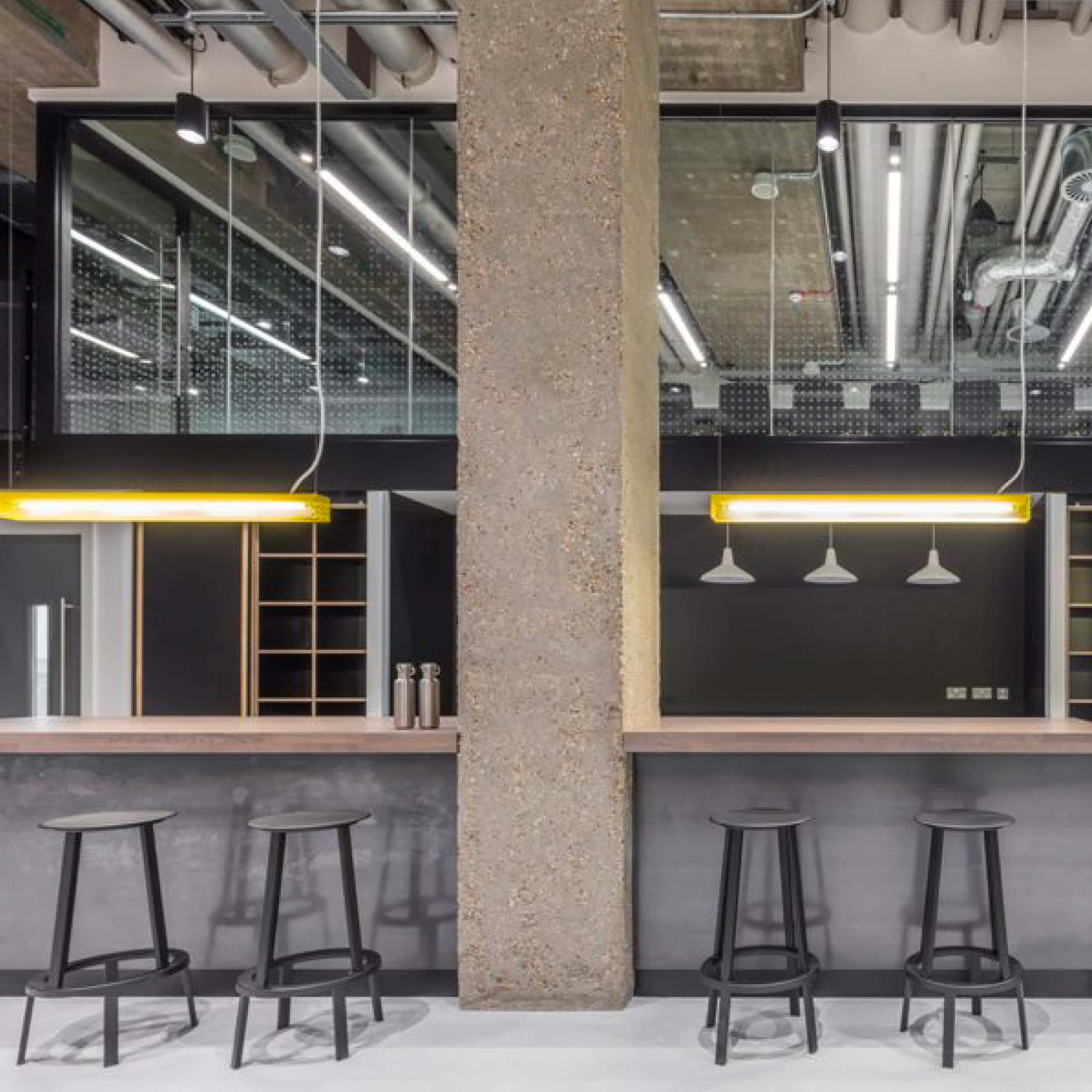 Industrial office bar area with concrete column, pendant lighting and tall stools