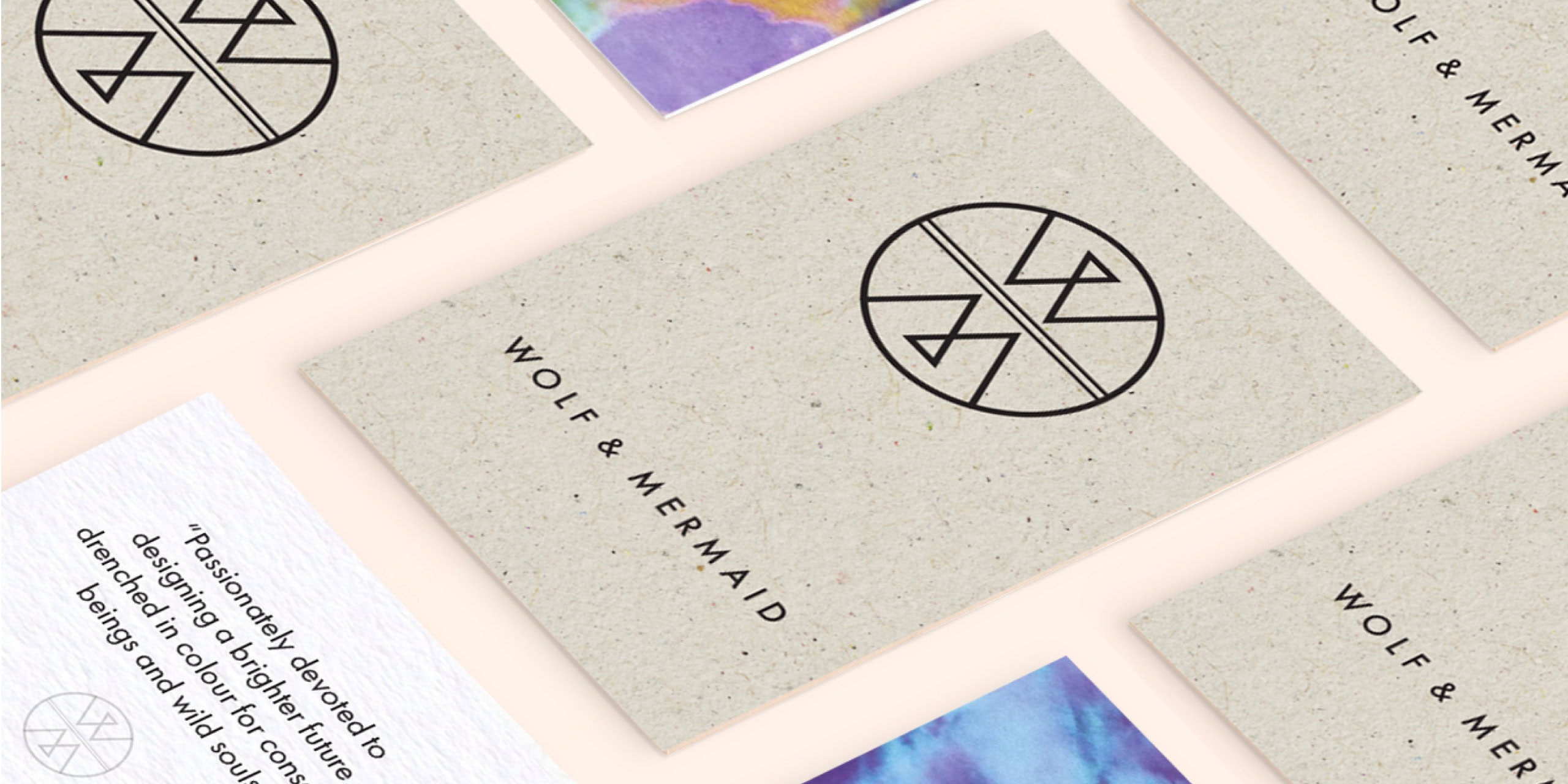 Wolf & Mermaid business cards and stationery laid out, showing the logo mark