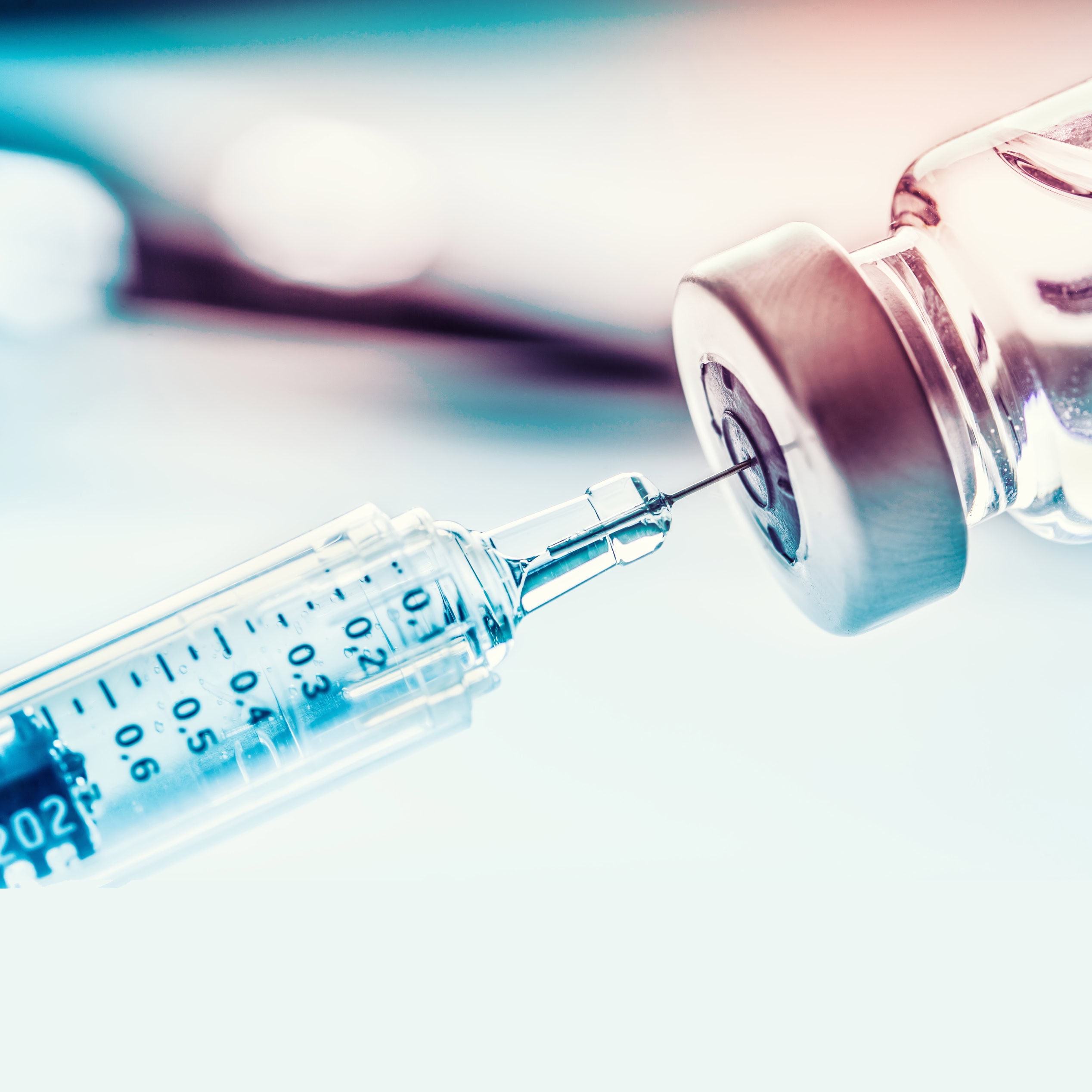 Close-up of a syringe drawing liquid from a medical vial