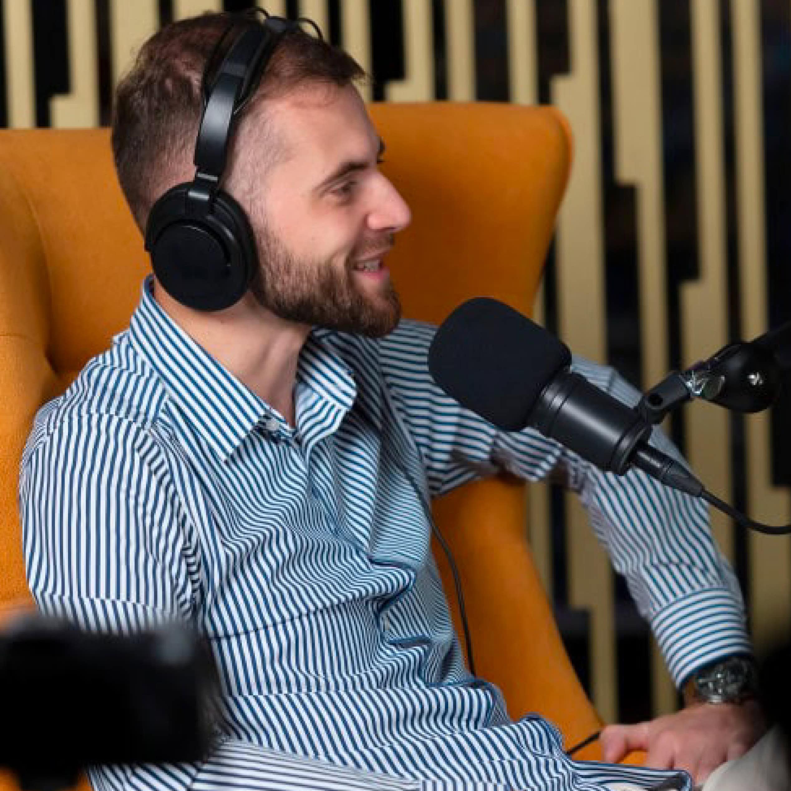 Man wearing headphones speaking into a microphone during a podcast recording