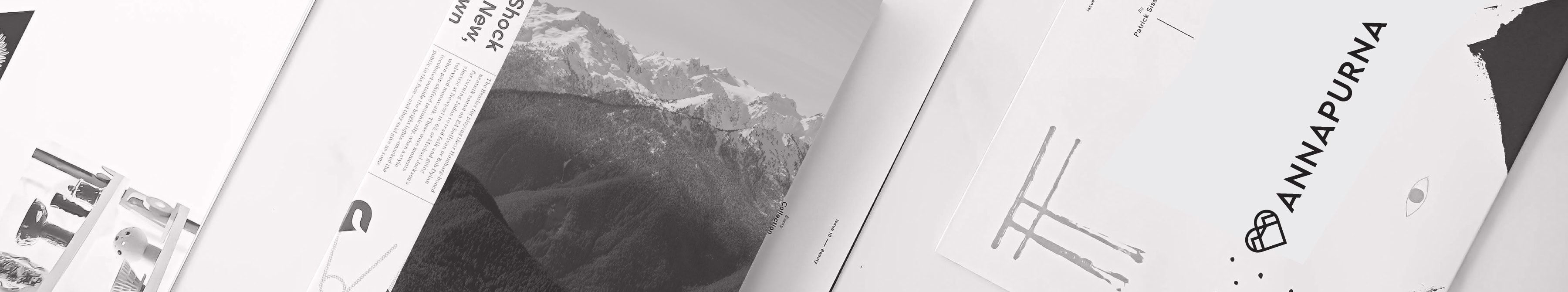 Flat lay of Annapurna branded print materials and magazine spreads featuring mountain imagery in monochrome.