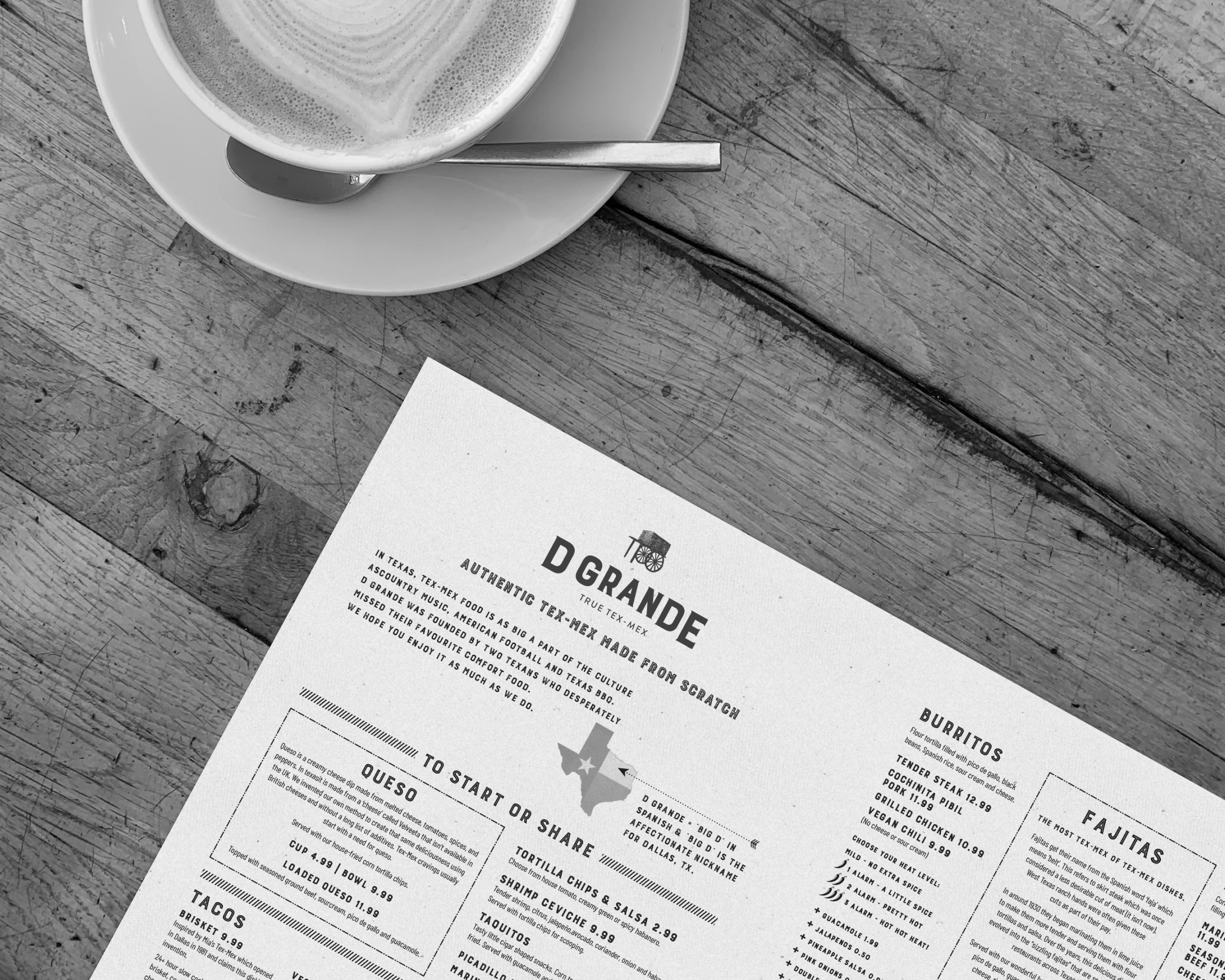 Coffee cup on a saucer beside a printed D Grande Tex-Mex menu on a rustic wooden table.